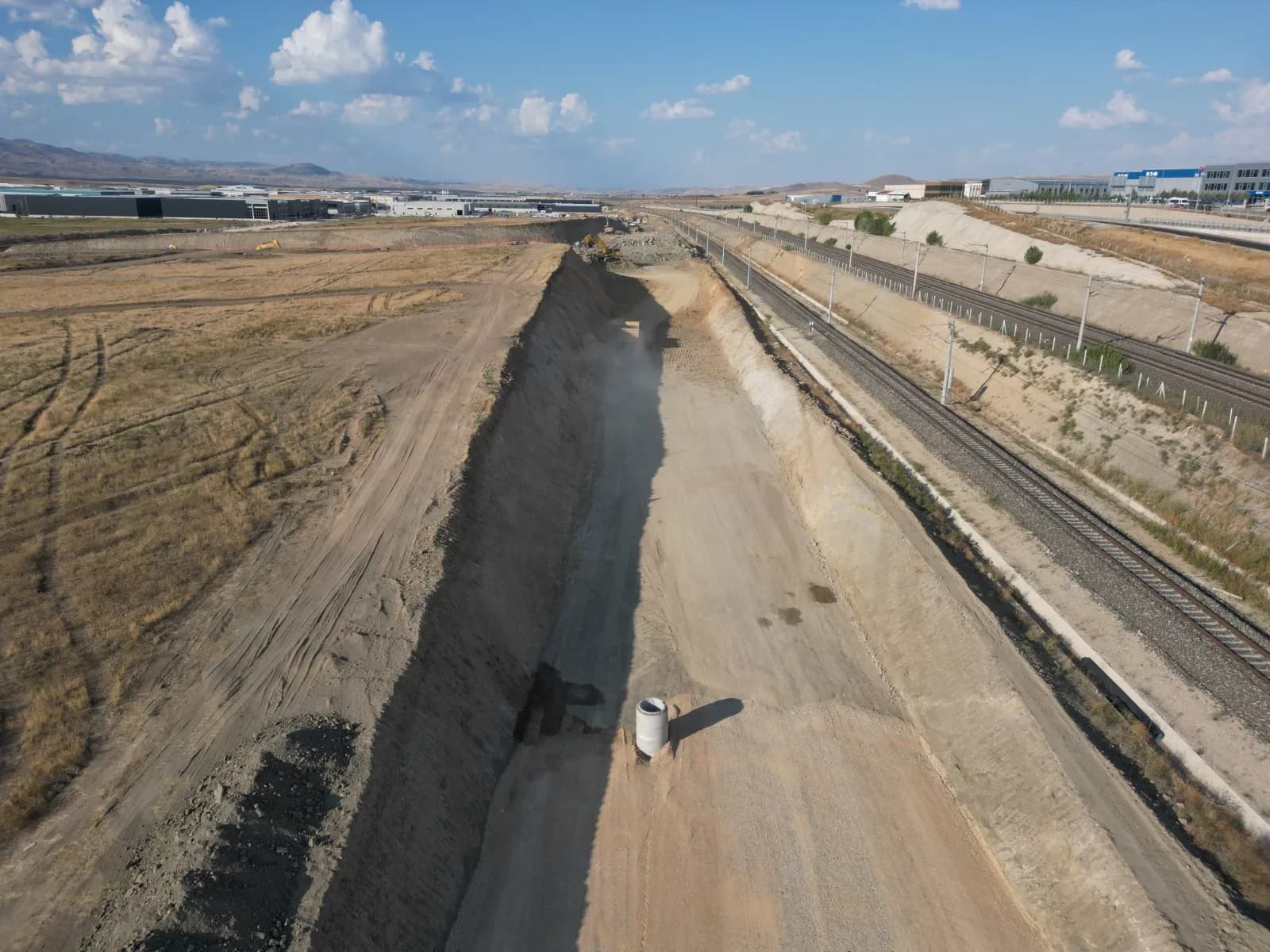 Başkent OSB genişleme bölgesinde demiryolu hattına paralel, kazısı tamamlanmış derin kanal; drone görüntüsü